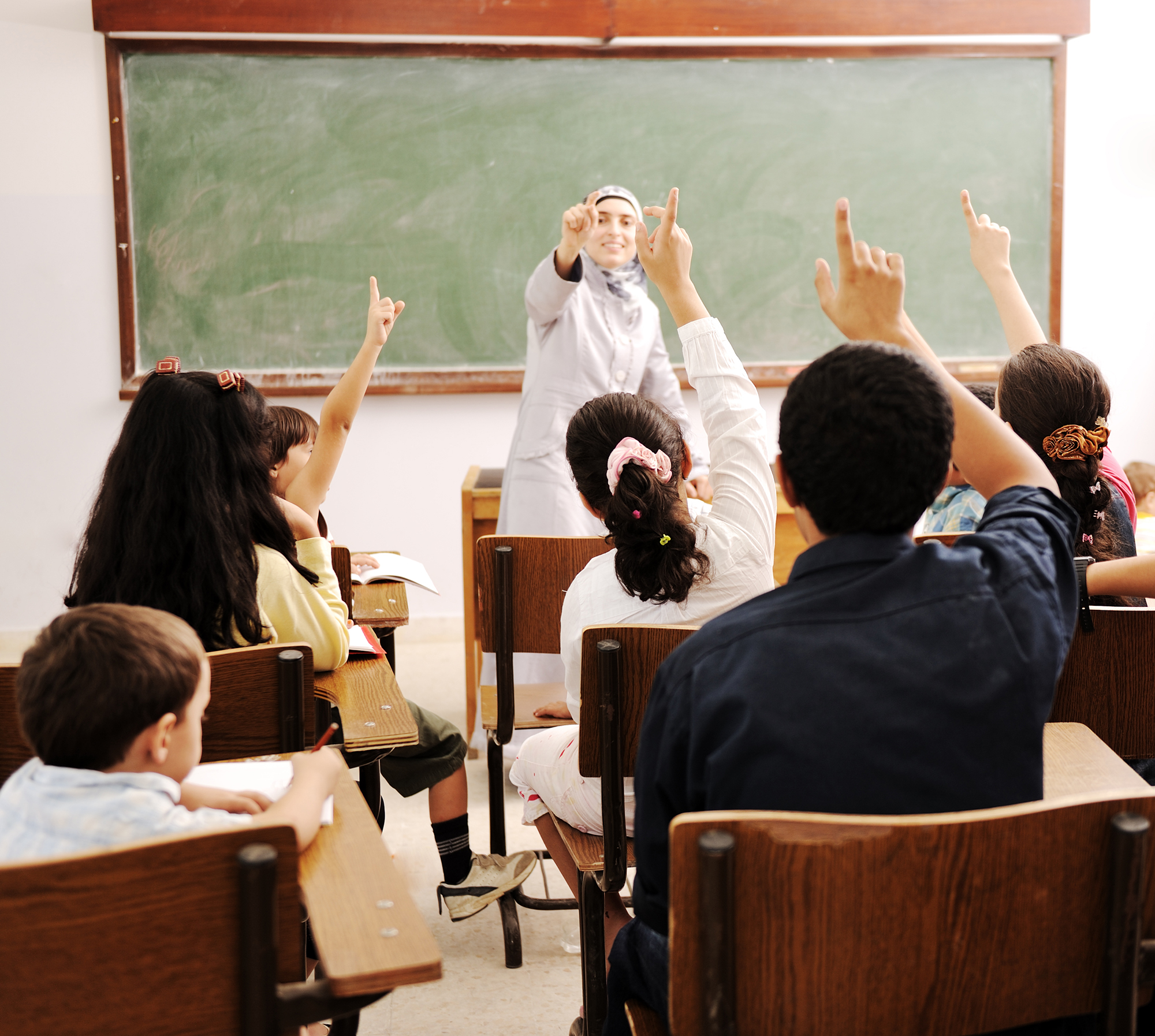 Happy children with their teacher in classroom, doing